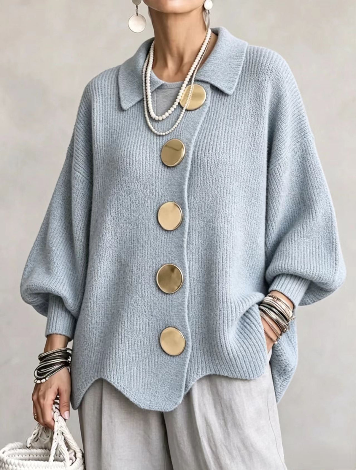 Cárdigan azul grisáceo con cuello y botones grandes, mostrado con mangas amplias y pantalones claros.