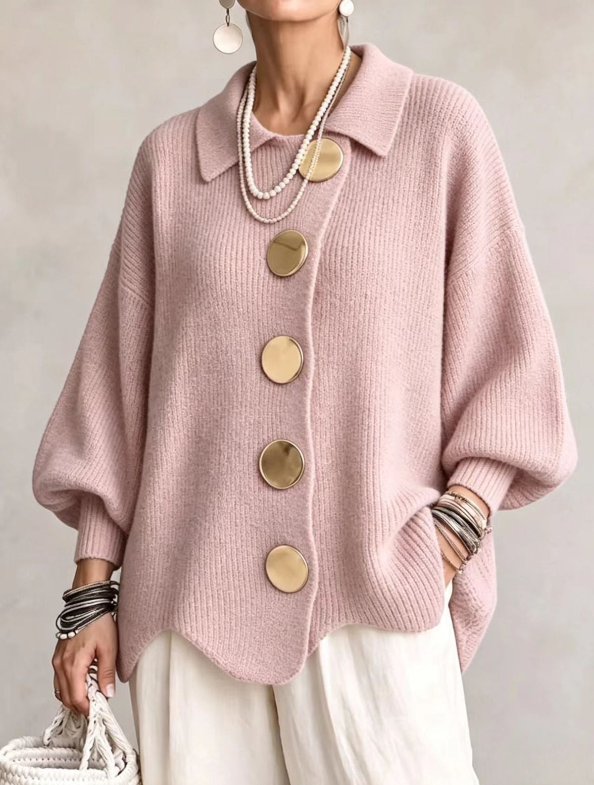 Cárdigan rosa pálido de corte holgado, con cuello redondeado, cinco botones grandes y bajo ondulado.