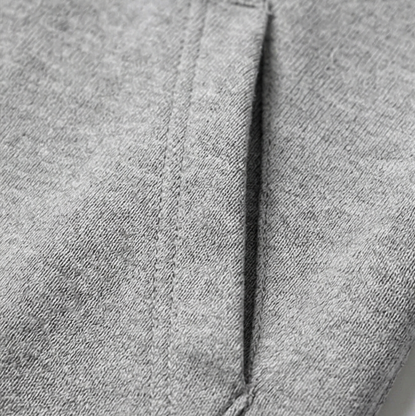 Detalle de una costura vertical y el borde de un bolsillo del cárdigan gris claro.