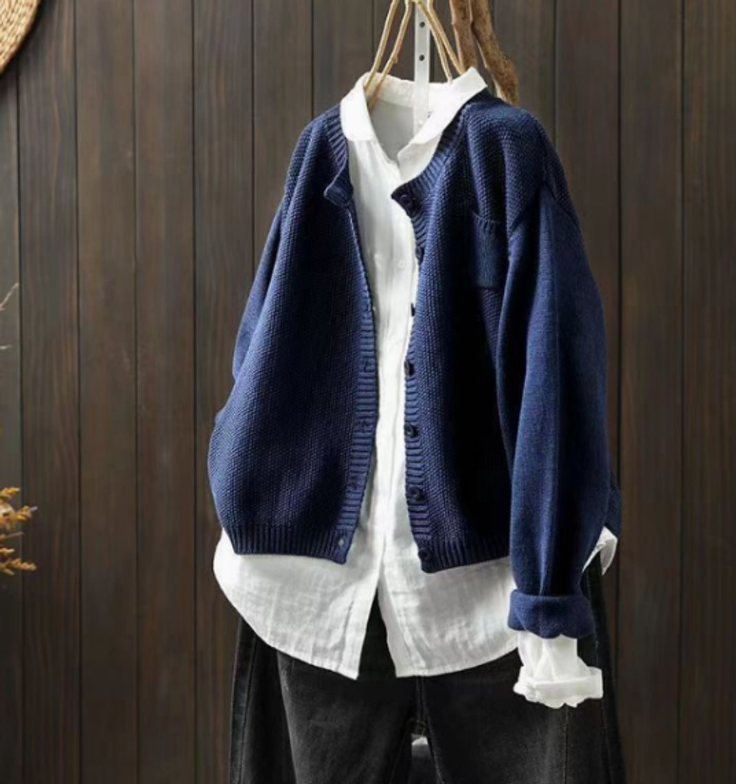Cárdigan azul marino de mangas largas y silueta holgada, abierto sobre camisa blanca y rematado con bordes acanalados.