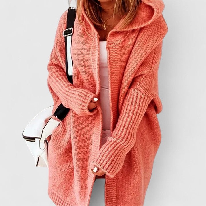 Cárdigan oversize coral con capucha llevado abierto, mostrado de frente con una prenda blanca debajo.