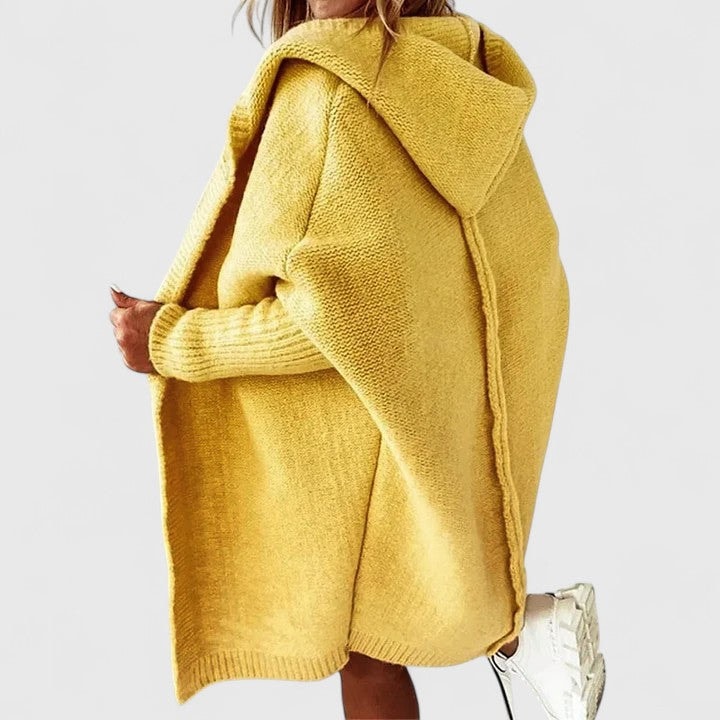 Cárdigan oversize amarillo mostaza con capucha, mostrado de perfil y con el bajo de punto visible.