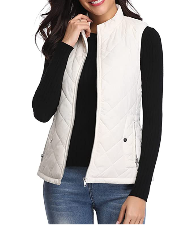 Chaleco acolchado blanco con cuello alto y cierre frontal abierto, combinado con jersey negro y vaqueros.