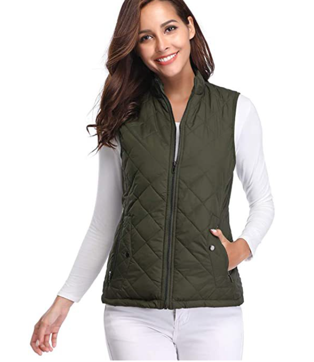Chaleco acolchado verde oliva con cuello alto y cierre frontal, combinado con pantalón blanco y un bolsillo parcialmente abierto.