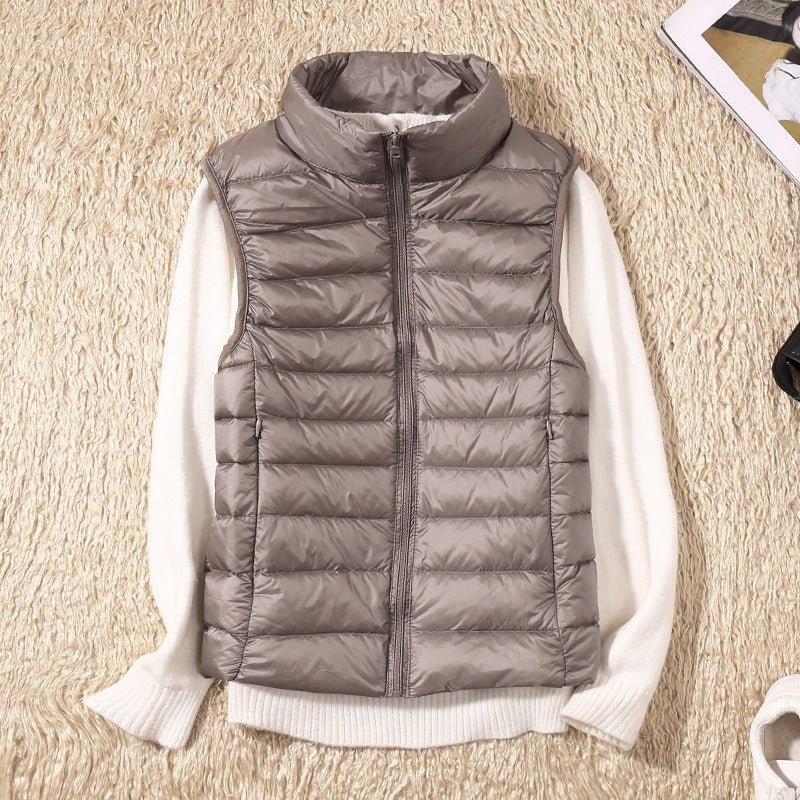 Chaleco acolchado gris topo visto de frente sobre un jersey de manga larga, con paneles horizontales y bolsillos laterales.