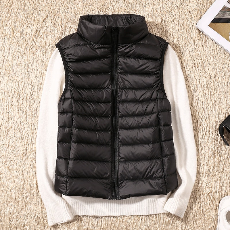 Chaleco acolchado negro de corte entallado sobre un jersey claro, mostrado cerrado con cuello alto.