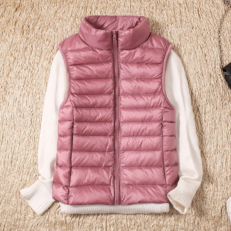 Chaleco acolchado rosa empolvado sobre un jersey blanco, con detalles fruncidos visibles en los laterales.