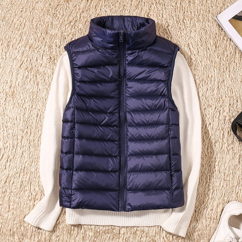Chaleco acolchado azul marino sobre un jersey de punto claro, con cuello alto y bolsillos laterales discretos.