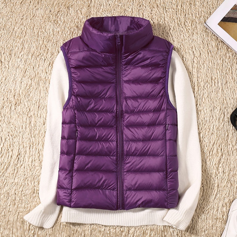 Chaleco acolchado morado de corte entallado sobre un jersey blanco, con cuello alto y bolsillos laterales.