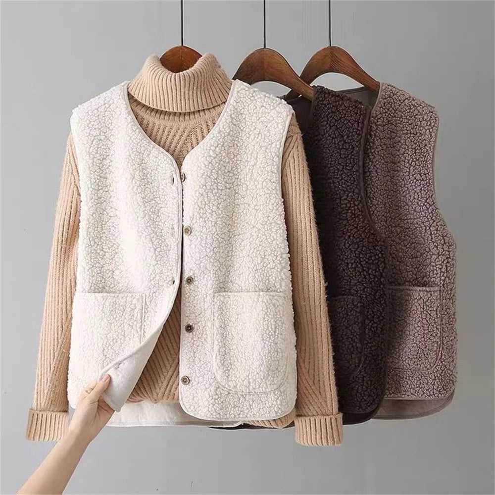 Chaleco blanco de efecto borreguito sobre un jersey de cuello alto, con botones frontales y bolsillos amplios; al fondo se ven otras opciones en tonos oscuros.