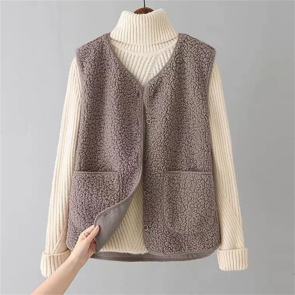 Chaleco gris topo de efecto borreguito combinado con un jersey claro, mostrado de frente con el borde interior levantado en la parte inferior.