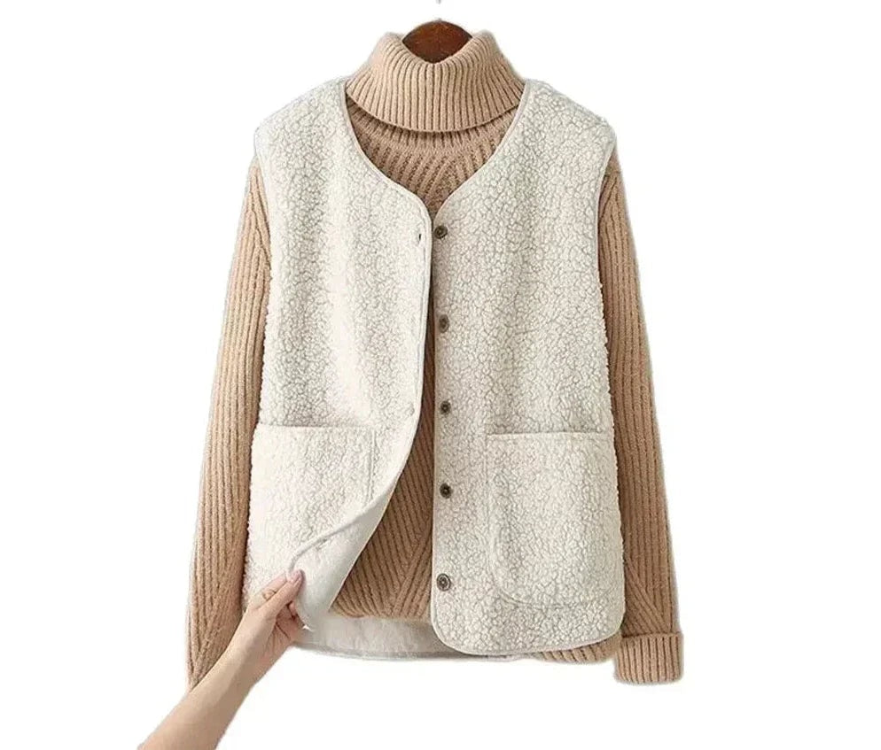Chaleco blanco de efecto borreguito sobre jersey de cuello alto beige, presentado contra fondo blanco con un bolsillo frontal parcialmente levantado.