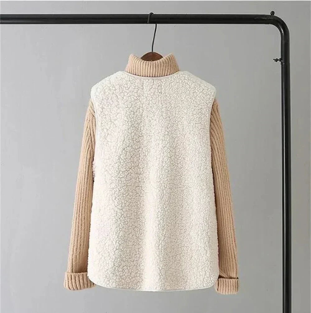 Vista trasera de un chaleco blanco de efecto borreguito, con espalda lisa, bajo redondeado y jersey beige visible en las mangas.