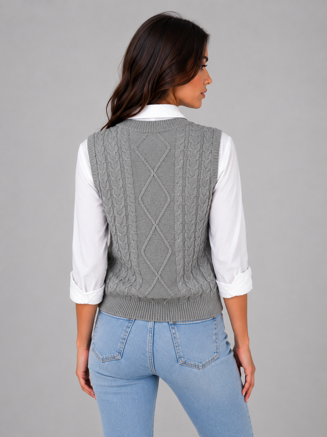 Vista trasera del chaleco gris de punto, con trenzas y panel central de rombos sobre una camisa blanca.