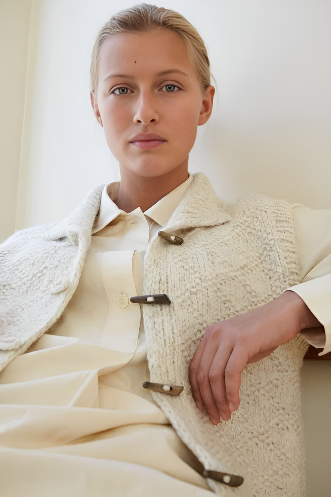 Chaleco de punto grueso con cuatro alamares sobre una camisa clara, visto en un conjunto de estilo elegante.