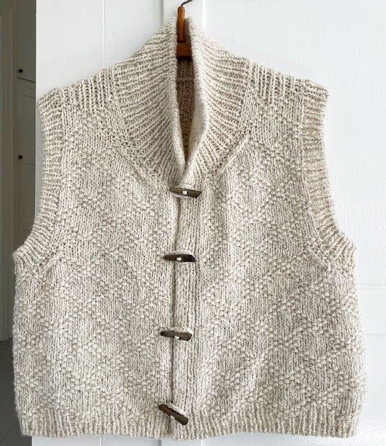 Chaleco completo colgado, con diseño sin mangas, cuello alto, cuatro alamares y dibujo de rombos.