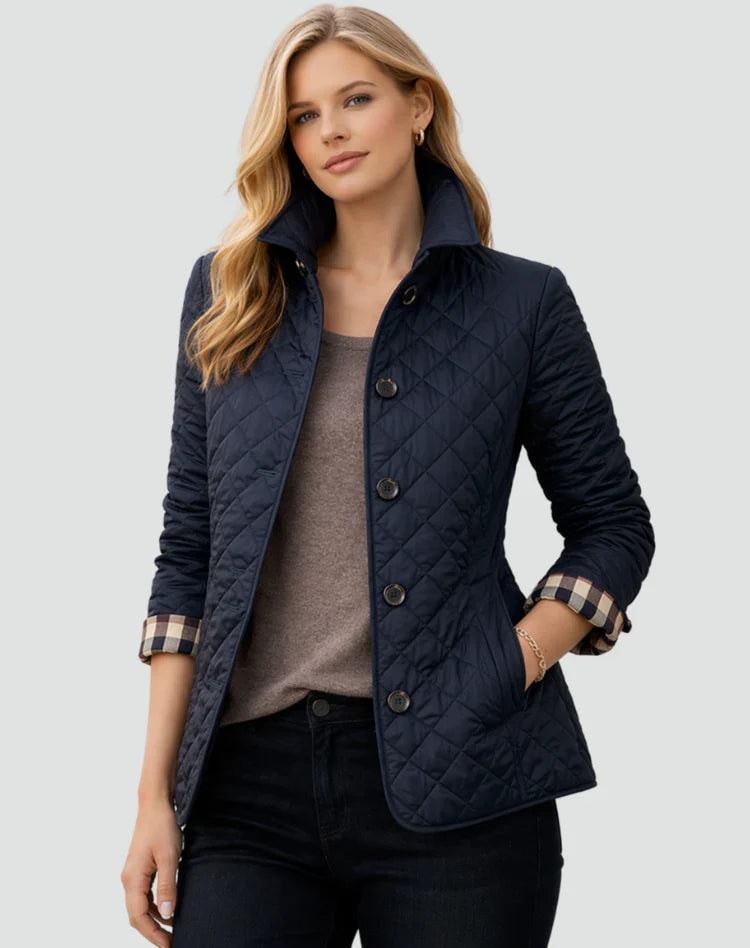 Chaqueta acolchada azul marino con cuello elevado, botones frontales y puños vueltos a cuadros.