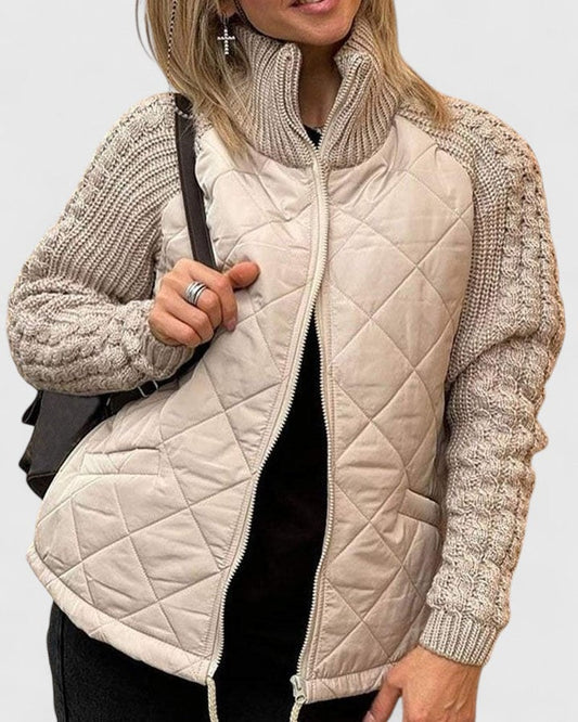 Chaqueta acolchada en tono claro con mangas de punto trenzado, cuello alto, cierre frontal abierto y bolsillos laterales.