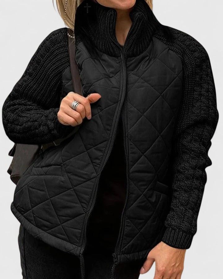 Chaqueta acolchada negra con mangas y cuello de punto a juego, mostrada de frente con el cierre abierto.