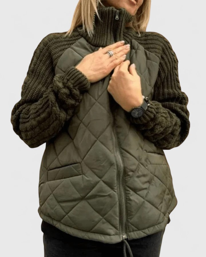 Chaqueta acolchada en tono verde oliva con mangas de punto oscuro, mostrada cerrada y con las manos junto al cuello.