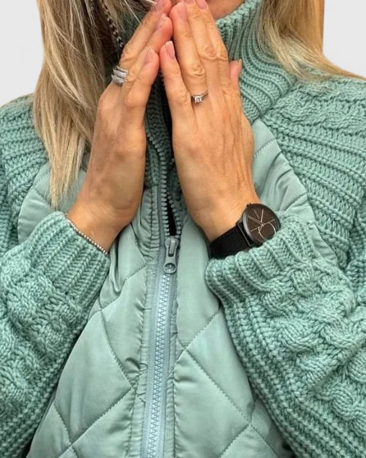 Detalle cercano del cuello alto de punto, el cierre frontal y las mangas trenzadas de la chaqueta verde claro.