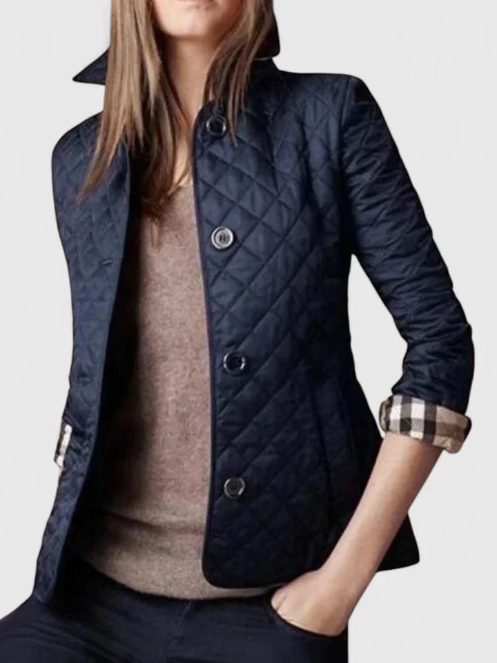 Chaqueta acolchada azul marino con corte entallado, cuello alto y mangas remangadas con puños de cuadros.