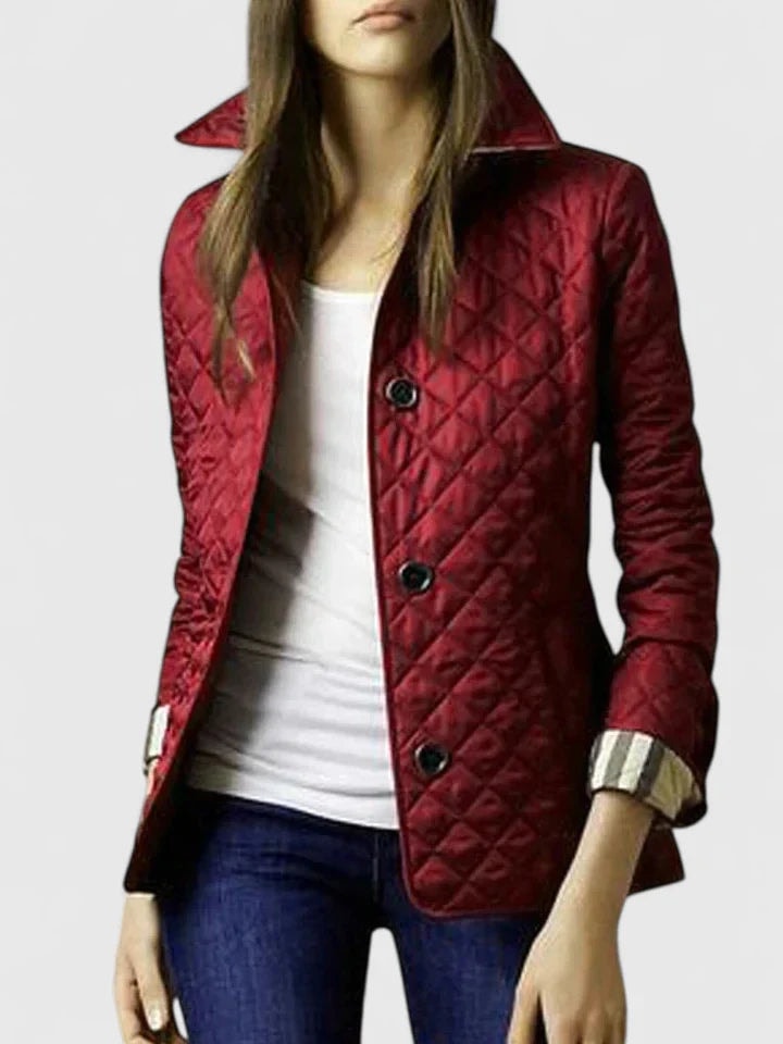 Chaqueta acolchada roja entallada con cuello alto levantado, botones oscuros y puños de cuadros vueltos.