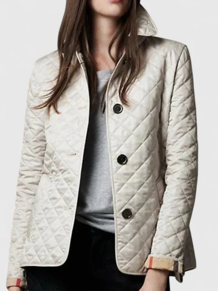 Chaqueta acolchada blanca de corte entallado, con cuello alto, botones negros y acabado claro.