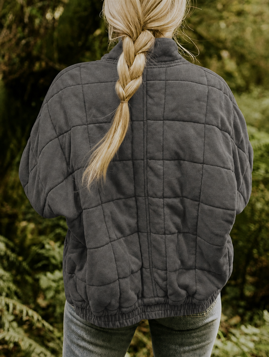 Vista posterior de la chaqueta acolchada gris, con diseño de cuadros y bajo elástico.