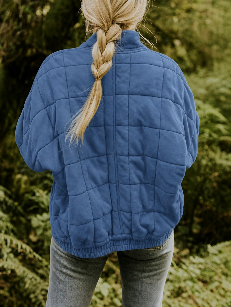 Vista posterior de la chaqueta acolchada azul, con paneles de cuadros y bajo elástico.