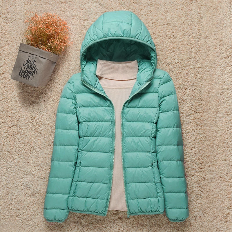 Chaqueta acolchada ligera de color turquesa con capucha, cierre frontal abierto y bolsillos laterales.