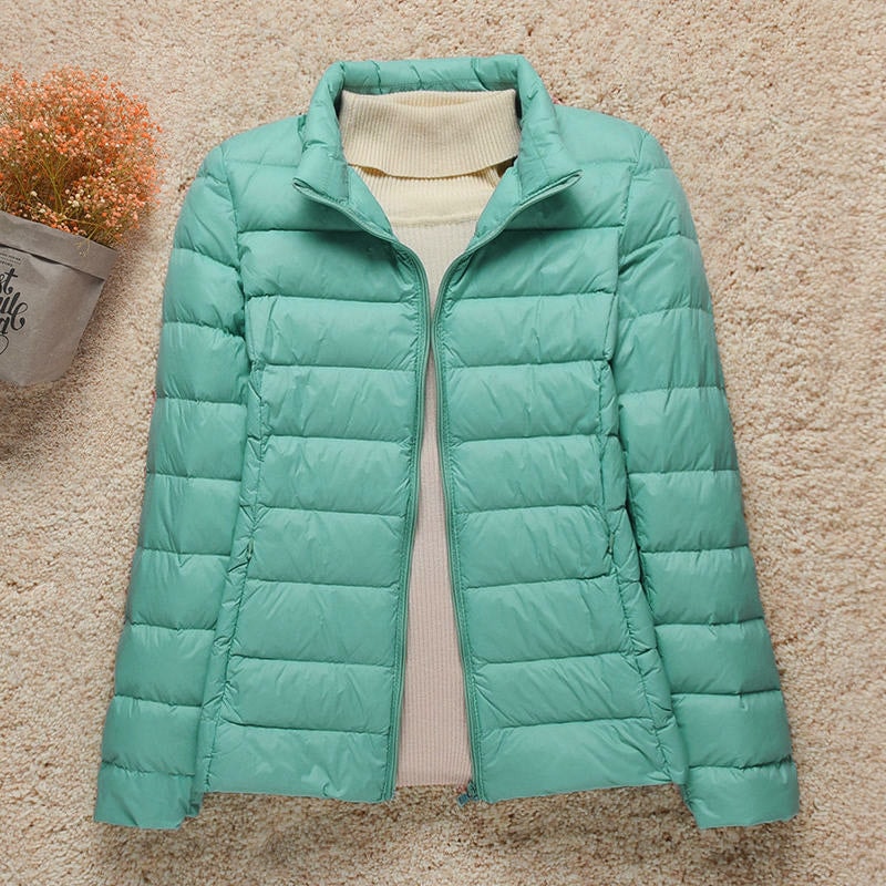 Chaqueta acolchada verde menta con cuello alto en lugar de capucha y cremallera frontal abierta.