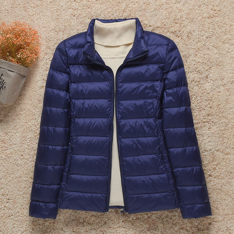 Chaqueta acolchada azul marino con cuello alto y cierre frontal abierto, mostrando su diseño entallado.