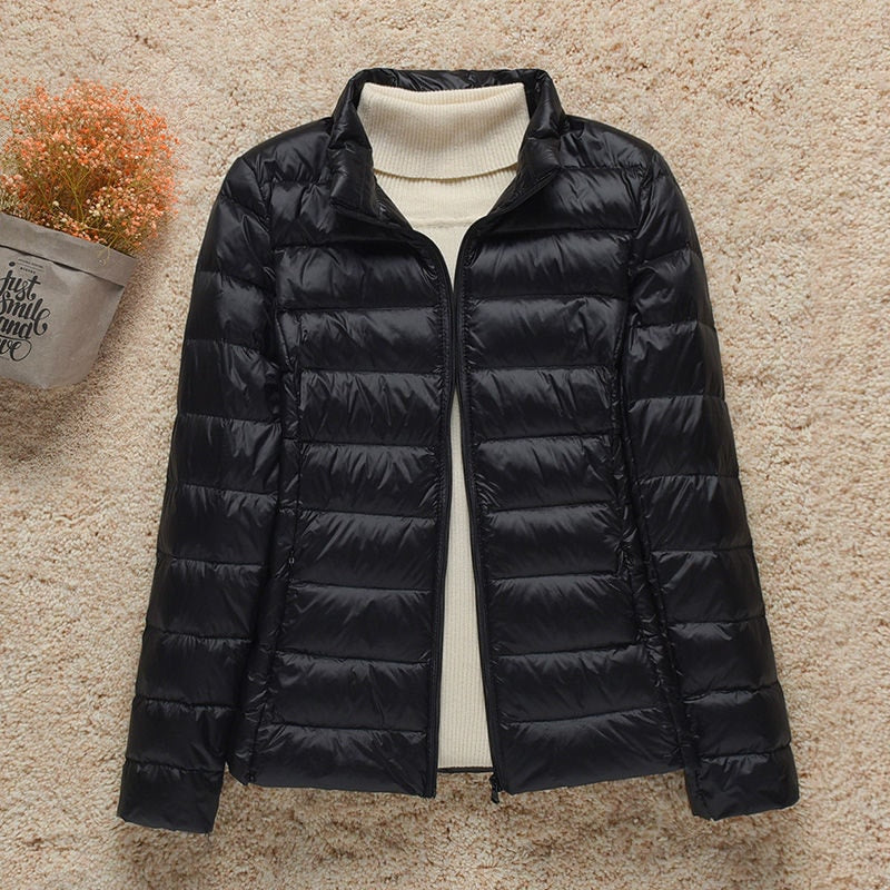 Chaqueta acolchada negra con cuello alto, cremallera frontal abierta y bolsillos laterales integrados.