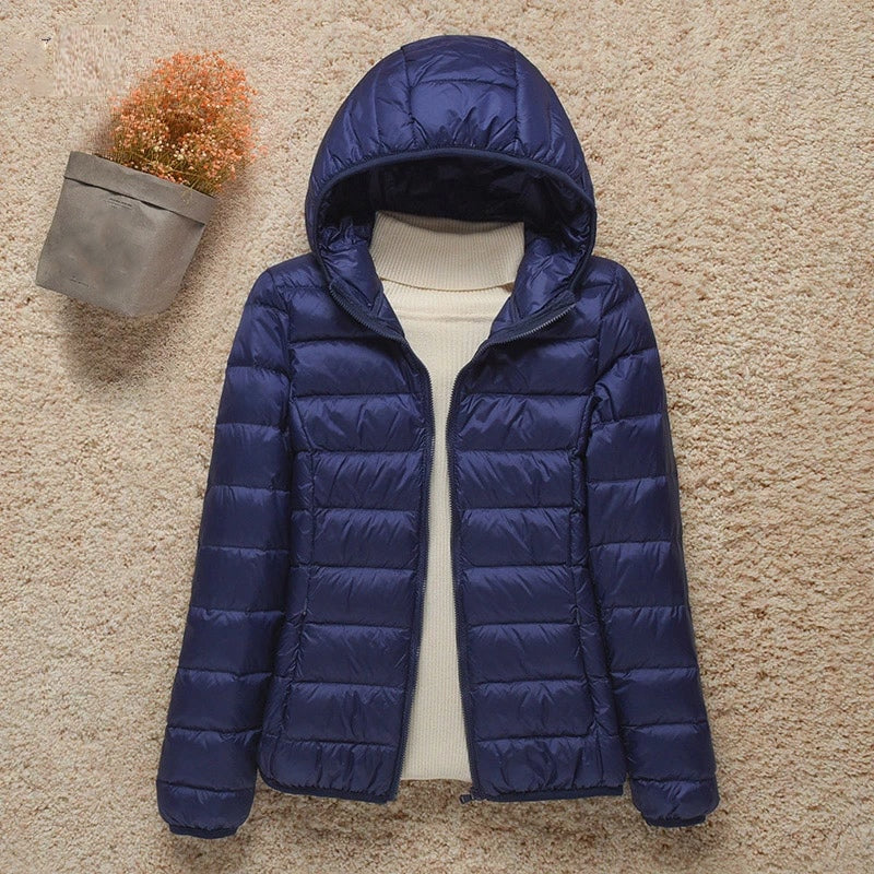 Chaqueta acolchada azul marino con capucha, cremallera frontal abierta y bolsillos laterales.