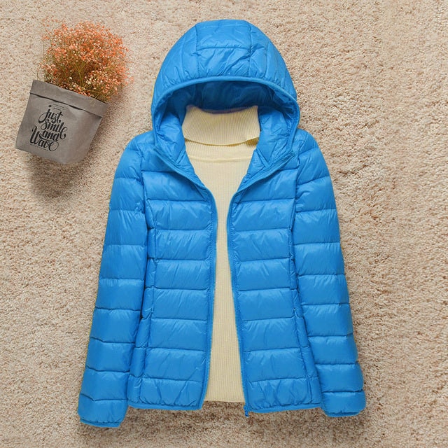 Chaqueta acolchada azul brillante con capucha y bolsillos laterales, extendida con el cierre abierto.