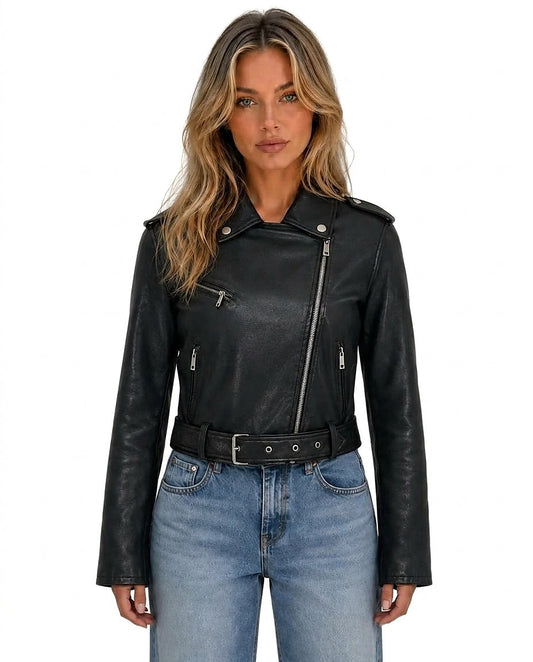 Chaqueta biker corta negra con cierre asimétrico, solapas, bolsillos con cremallera y cinturón con hebilla, combinada con vaqueros.