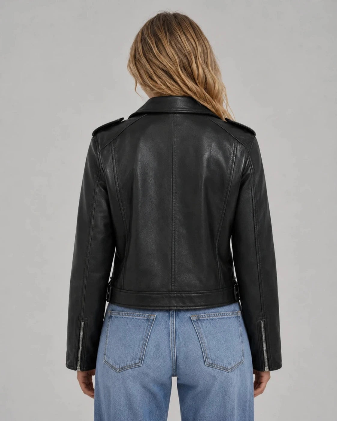 Vista posterior de una chaqueta biker corta negra, con cuello de solapas, hombreras y costuras verticales.