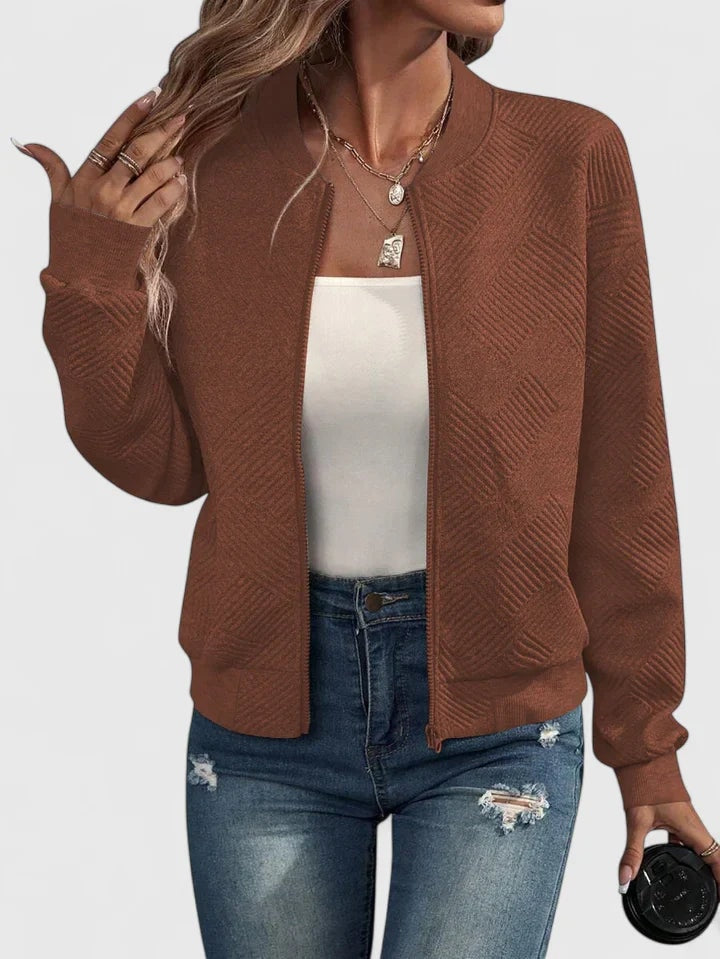 Chaqueta bomber marrón con textura geométrica integral, cierre frontal y bolsillos laterales, llevada sobre una camiseta blanca.