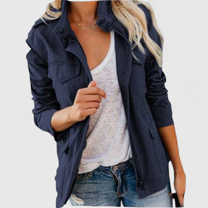 Chaqueta casual azul marino con cuello alto y bolsillos frontales, combinada con camiseta blanca y vaqueros.