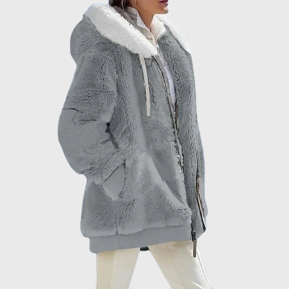 Chaqueta gris lisa con capucha clara, cordones y bolsillos laterales, vista de perfil con el cierre parcialmente abierto.