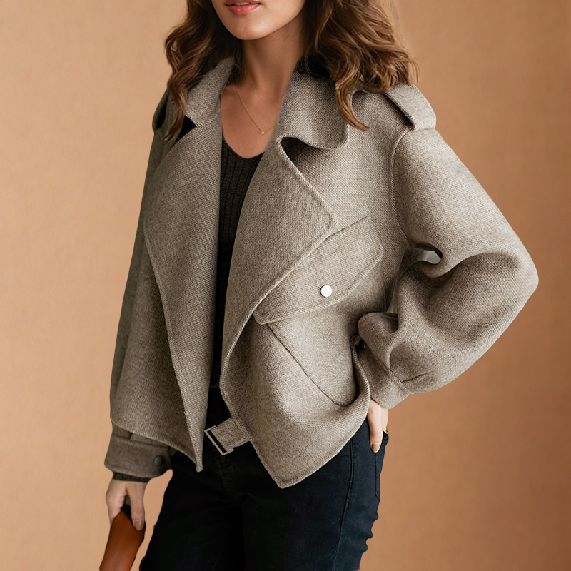 Chaqueta corta beige mostrada de frente, con solapas superpuestas, bolsillo con solapa y cinturón ajustado en la parte inferior.