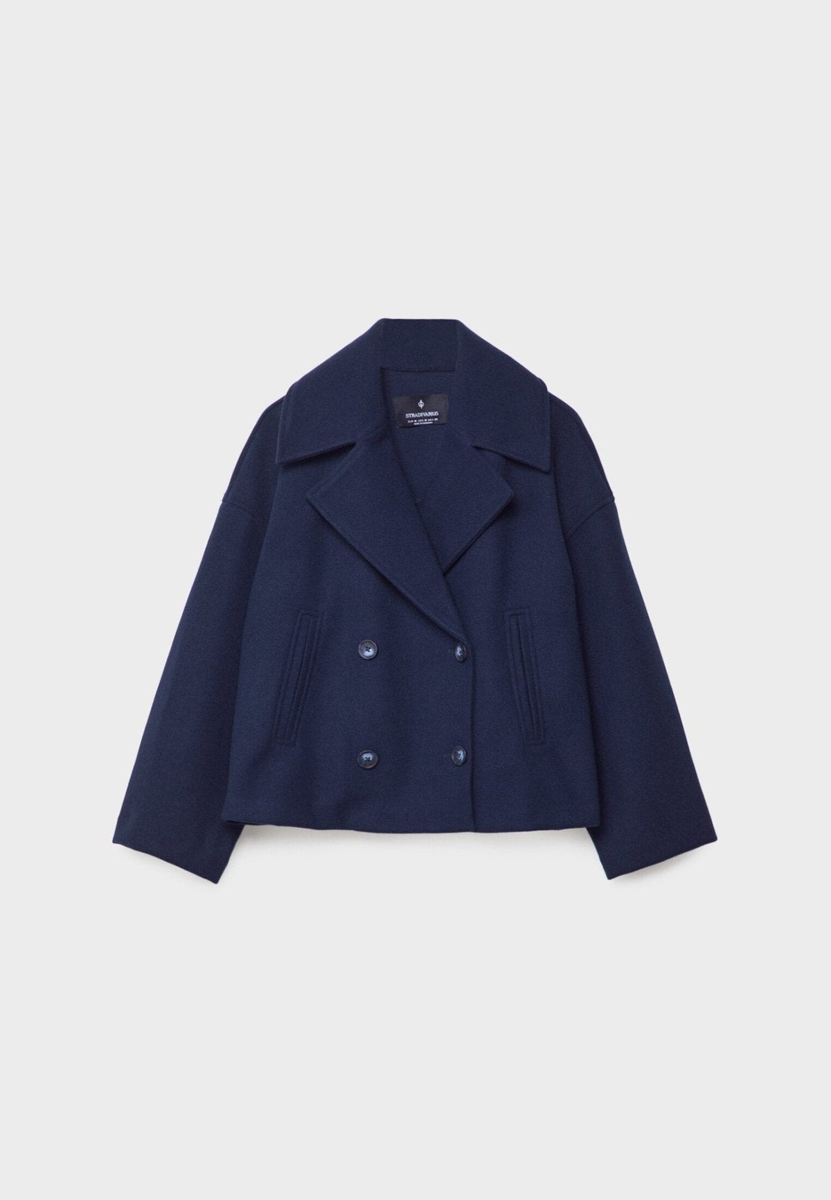 Chaqueta corta azul marino extendida de frente, con cuatro botones oscuros y corte corto.