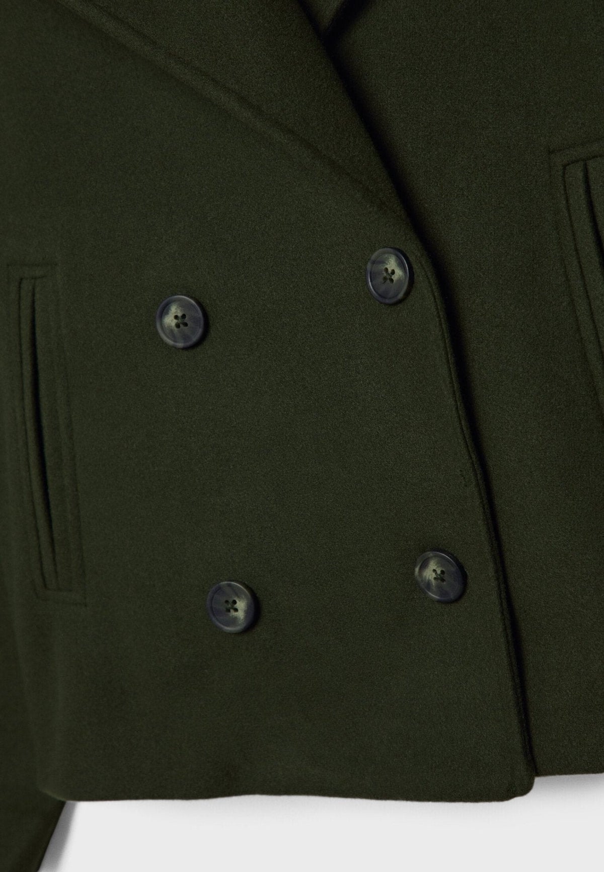Detalle frontal de la chaqueta verde oliva con cuatro botones oscuros y bolsillo vertical ribeteado.