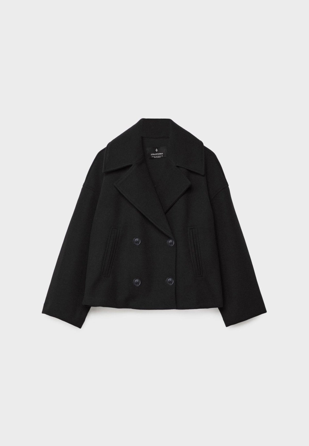 Chaqueta corta negra extendida de frente, con solapas amplias, doble fila de botones y bolsillos verticales.