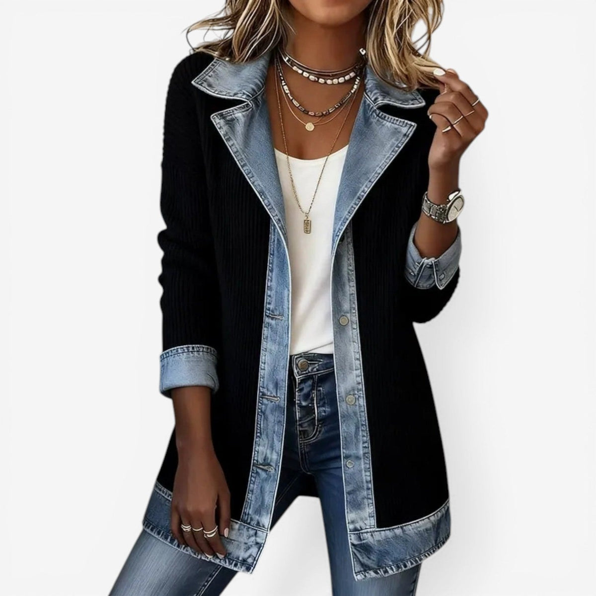 Chaqueta larga negra con solapas, puños y bajo en contraste azul, combinada con camiseta blanca y vaqueros.