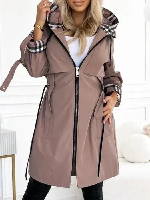 Gabardina topo con capucha y puños de contraste a cuadros, vista frontal con la cremallera cerrada y cinturón lateral visible.