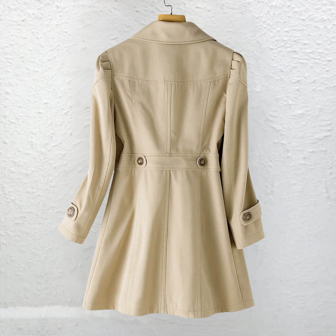 Gabardina entallada color beige vista por la espalda, con cinturón abotonado en la cintura, cuello amplio, mangas largas y falda acampanada.