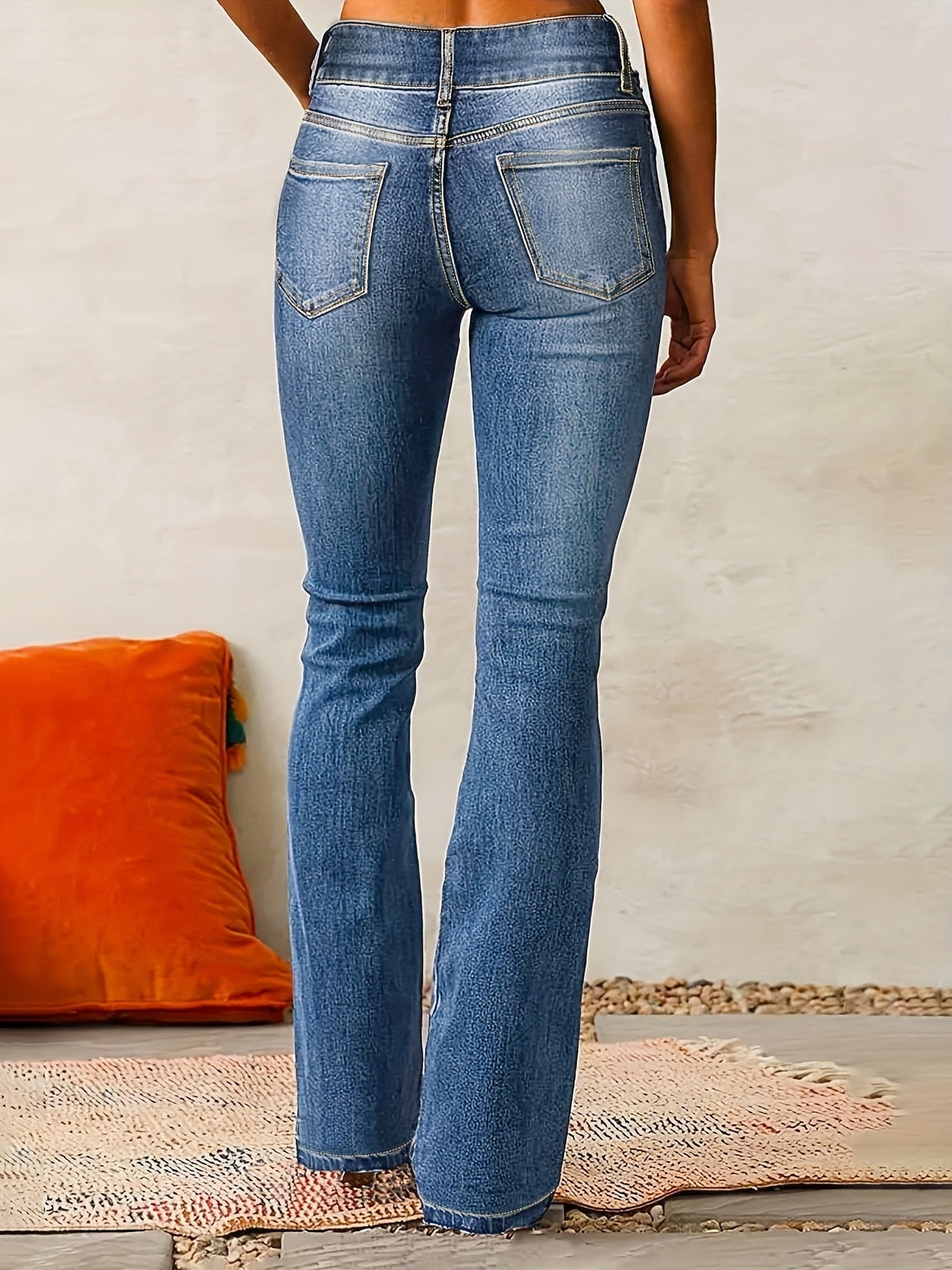 Vista posterior de los jeans azules, con pretina alta, costuras visibles y dos bolsillos traseros.