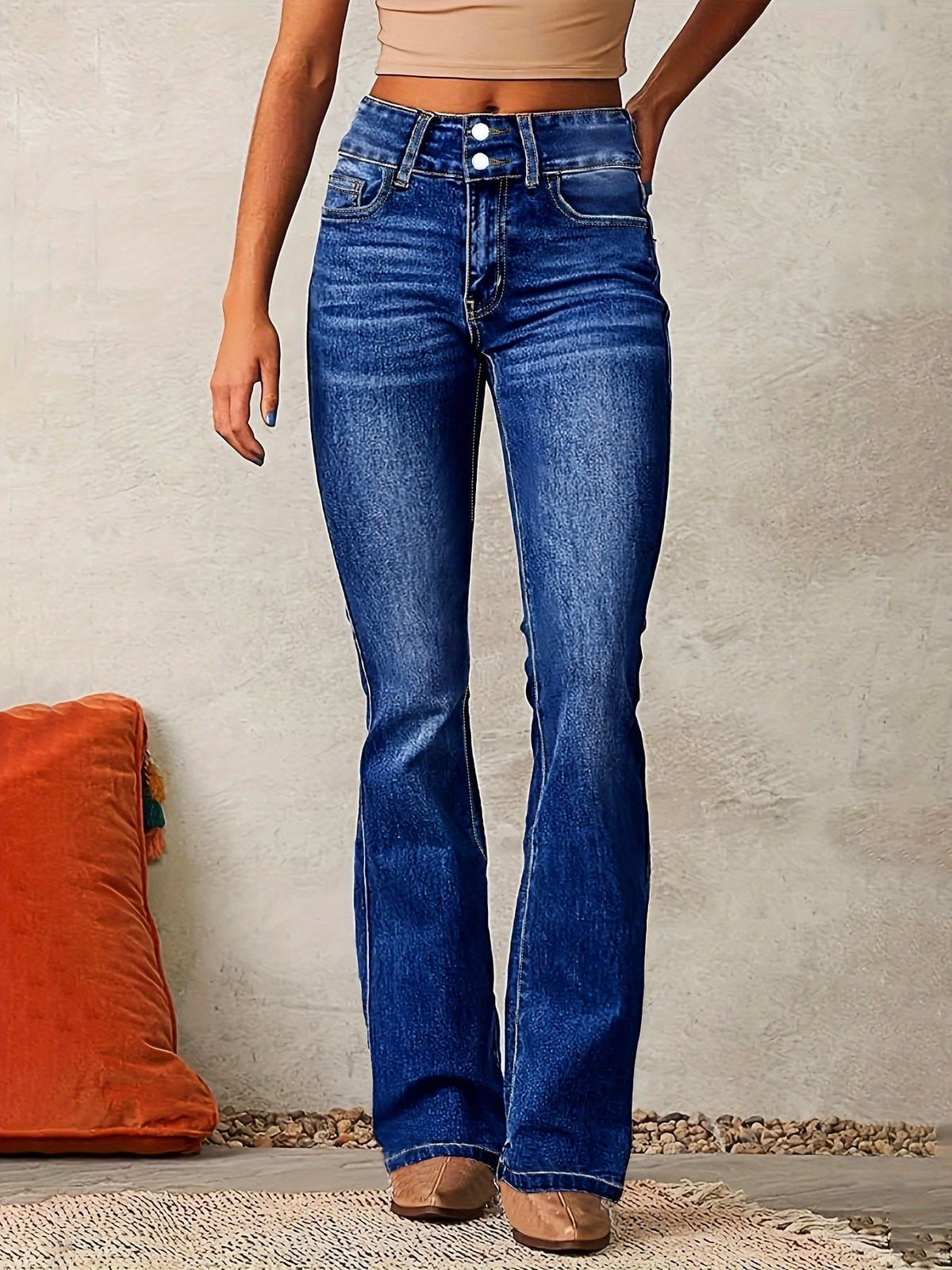 Detalle frontal de los jeans en tono azul intenso, con tiro alto, remaches metálicos y corte acampanado.